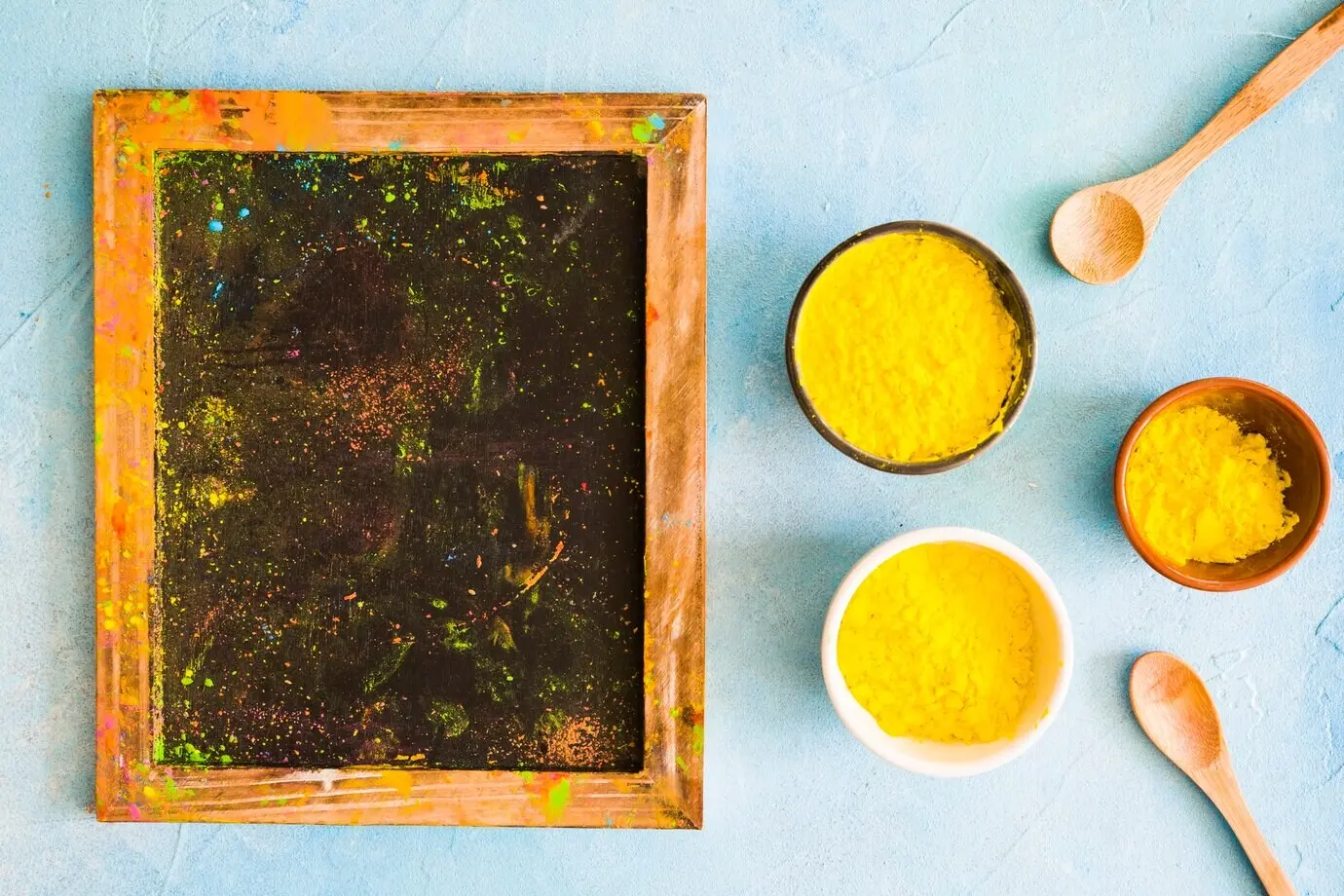 Unordentliche Schieferplatte mit Holi-Farbe auf blauem Betonhintergrund